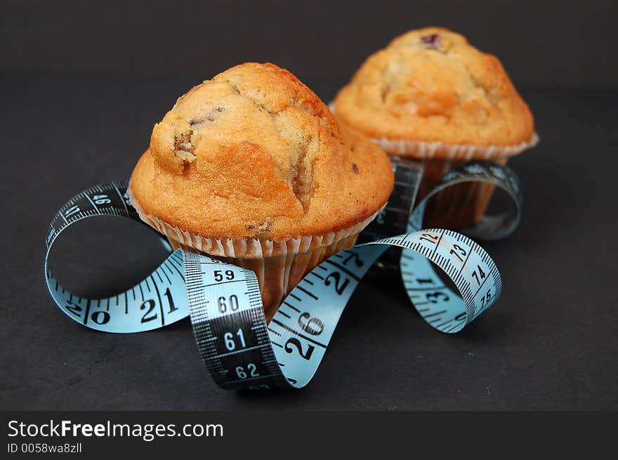 This is an image of blueberry muffins and a measuring tape. This is a metaphor for dieting. This is an image of blueberry muffins and a measuring tape. This is a metaphor for dieting.