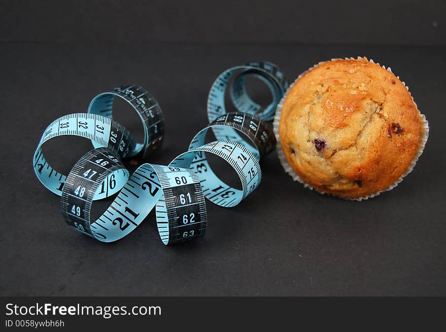 This is an image of a blueberry muffin and a measuring tape. This is a metaphor for dieting. This is an image of a blueberry muffin and a measuring tape. This is a metaphor for dieting.