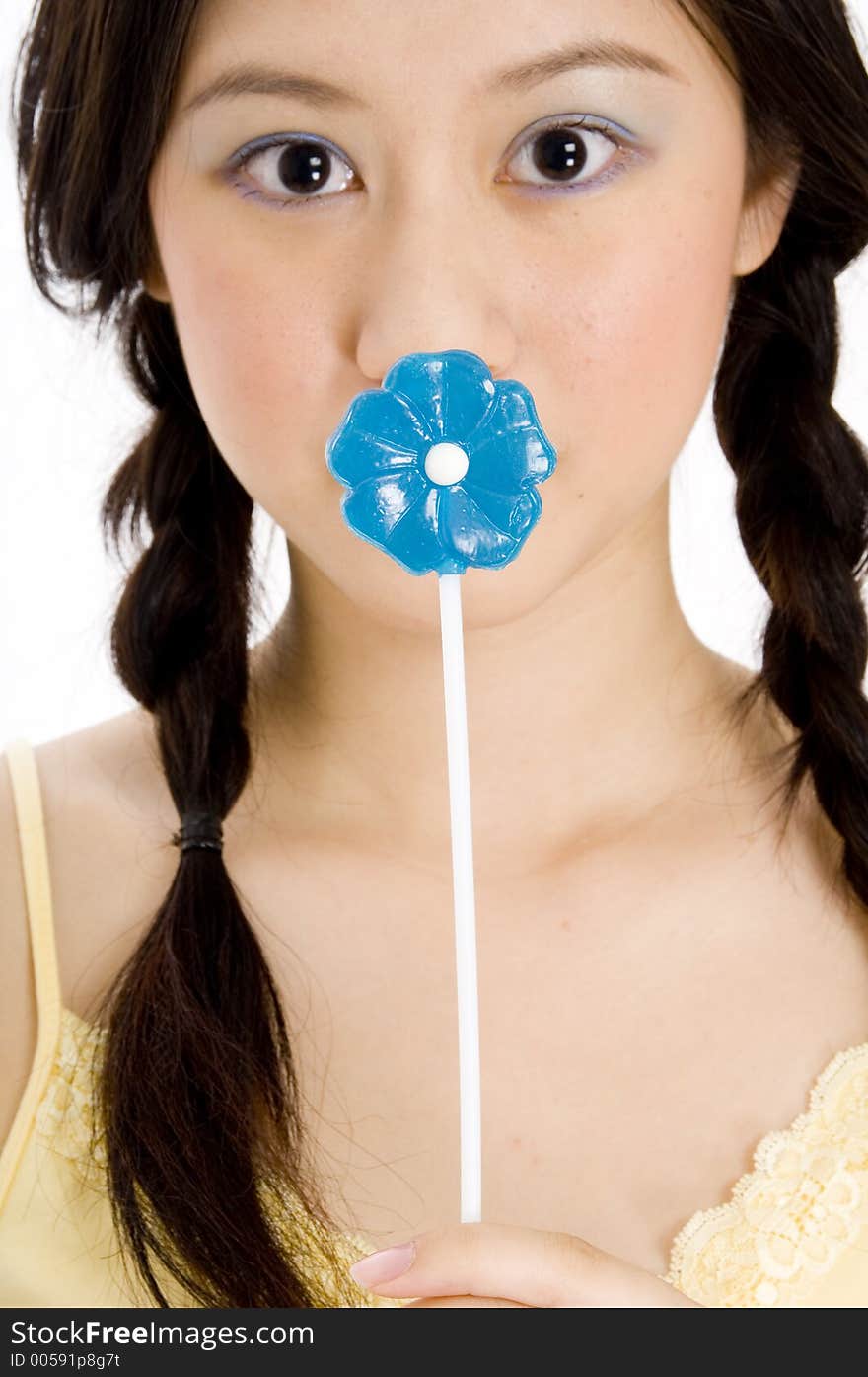 A young woman covers her mouth with a blue lollipop. A young woman covers her mouth with a blue lollipop