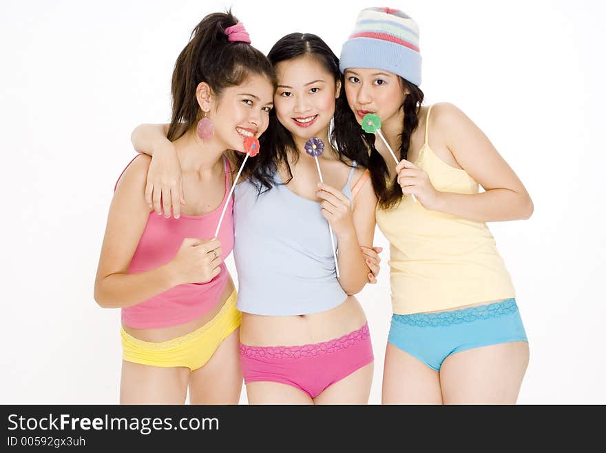 Three asian teenagers in colorful clothes with lollipops. Three asian teenagers in colorful clothes with lollipops