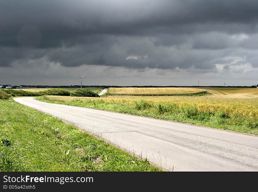 In the country nearby  a danish village in the summer, a road in the fields. In the country nearby  a danish village in the summer, a road in the fields