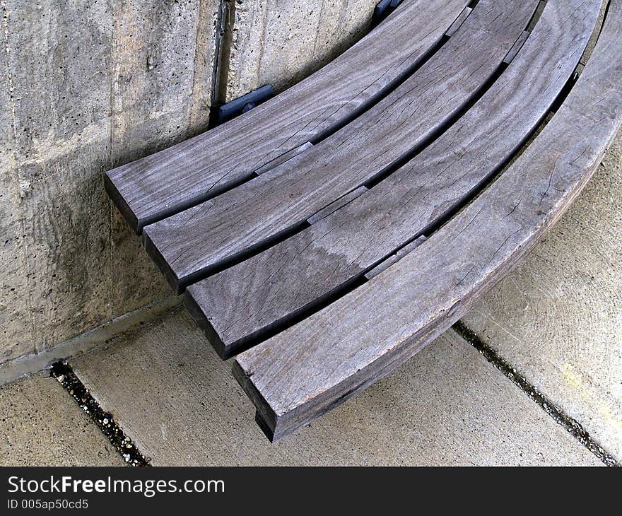 An urban plaza bench made of wood and concrete in strong light, shadow, and contrast. An urban plaza bench made of wood and concrete in strong light, shadow, and contrast.