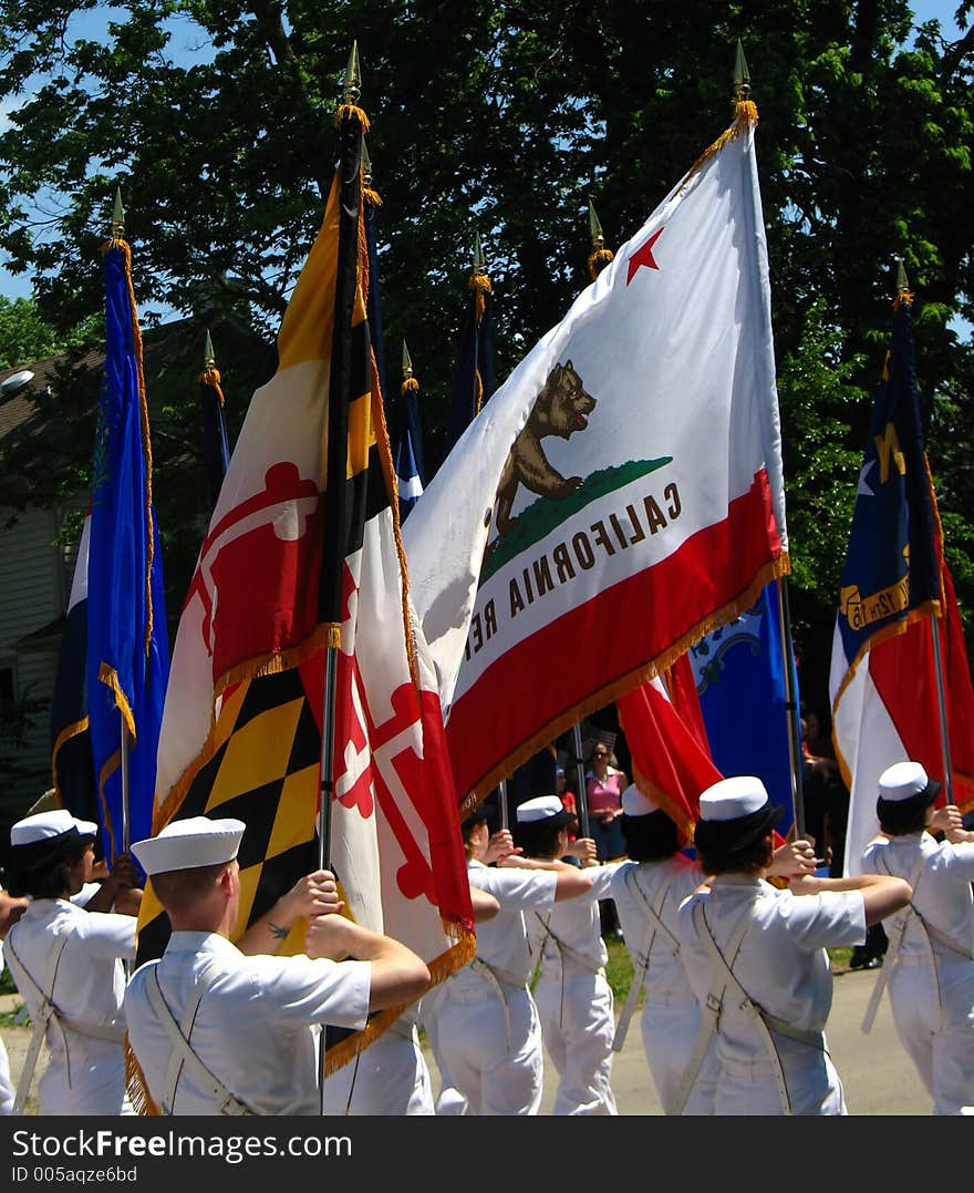 Military personnel holding flags while marching in parade. Military personnel holding flags while marching in parade