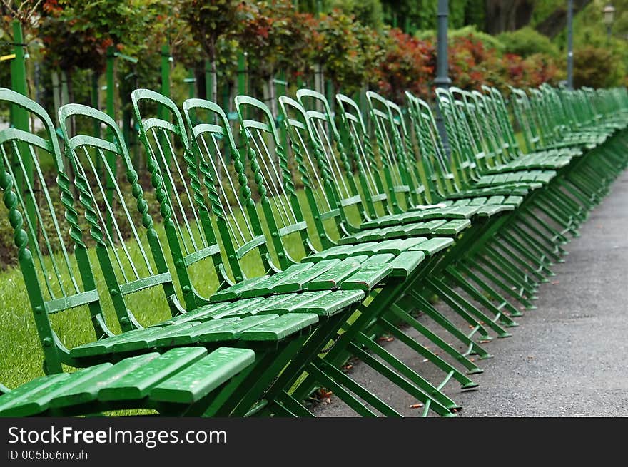 Row of green park benches after rain