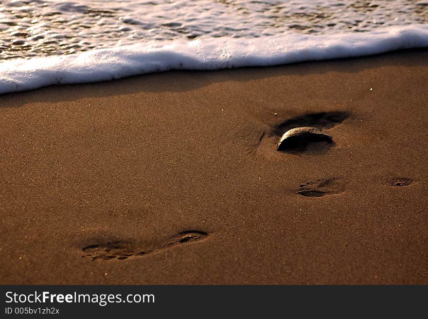 Footprints in the sand being washed away.