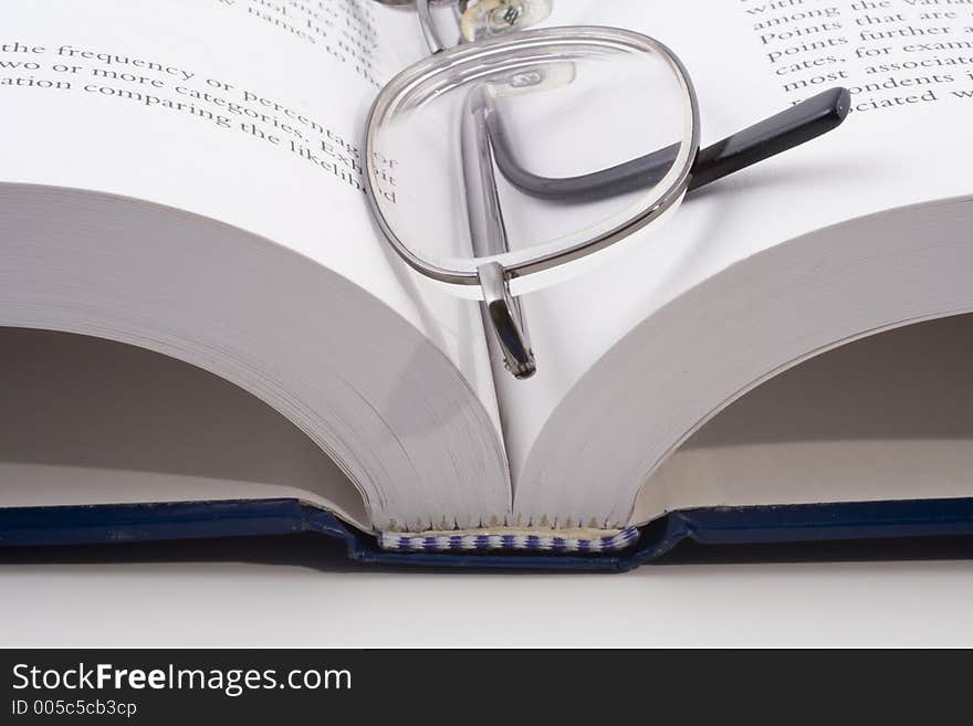 Close-up of an open book with eye-glasses