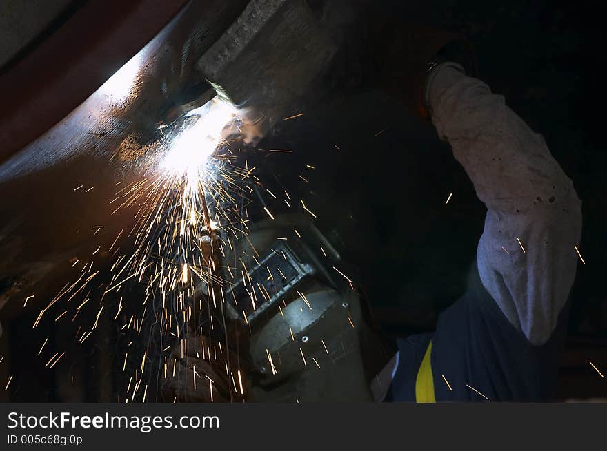 Welder leaning as he works under boat. Welder leaning as he works under boat