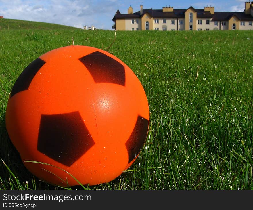 Orange ball with pentagon sign on the grass playing field

background sky and houses. Orange ball with pentagon sign on the grass playing field

background sky and houses