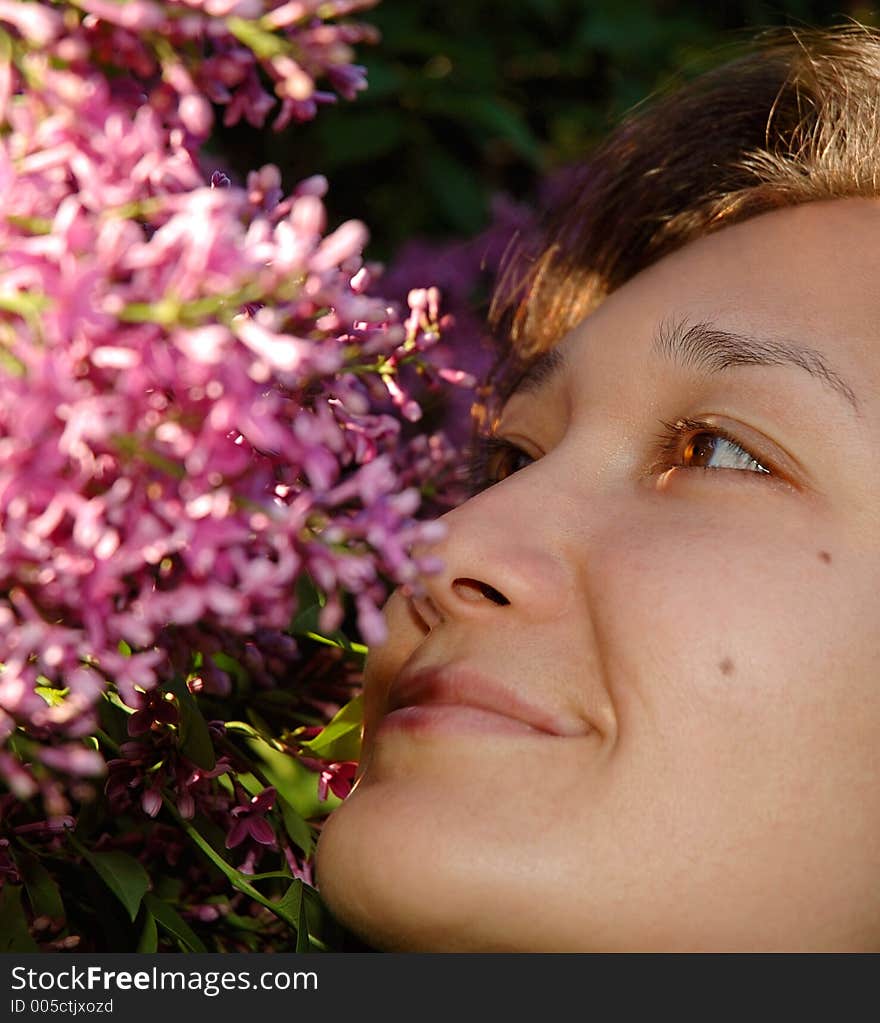 Happy Girl Smelling Liliac Flowers