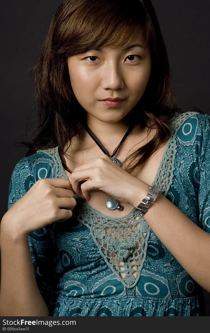 A beautiful young asian woman in patterned dress on black background. A beautiful young asian woman in patterned dress on black background