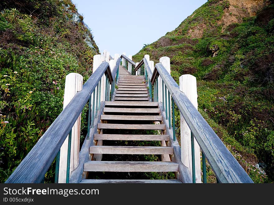 Outdoor wooden stairs at sunset leading to the beach.