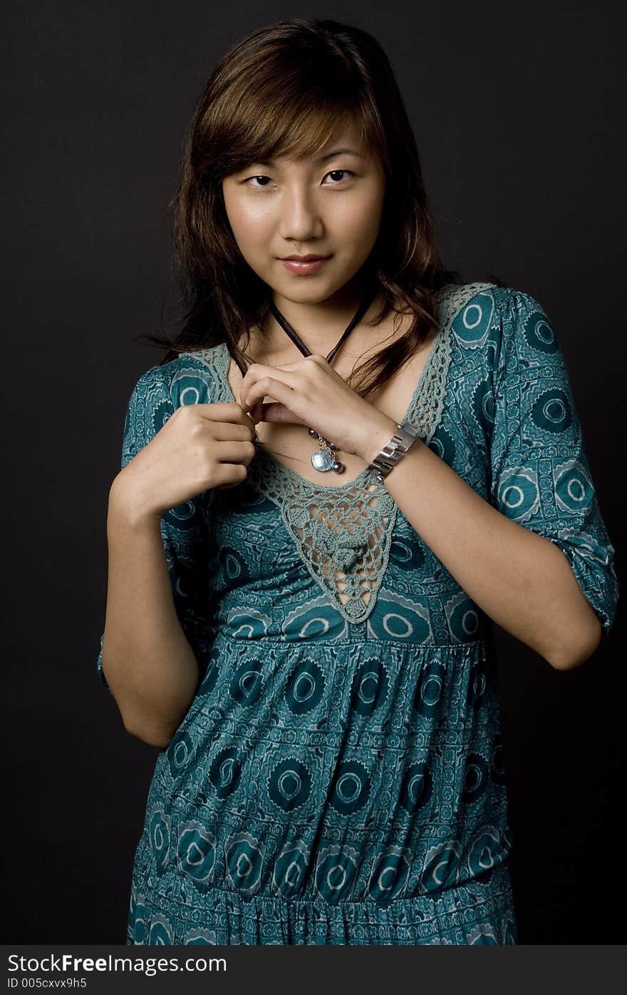 A pretty young asian woman in blue green dress on black background. A pretty young asian woman in blue green dress on black background