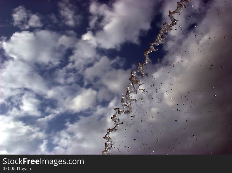 Water shot into the air, contrast against blue sky with clouds. Water shot into the air, contrast against blue sky with clouds