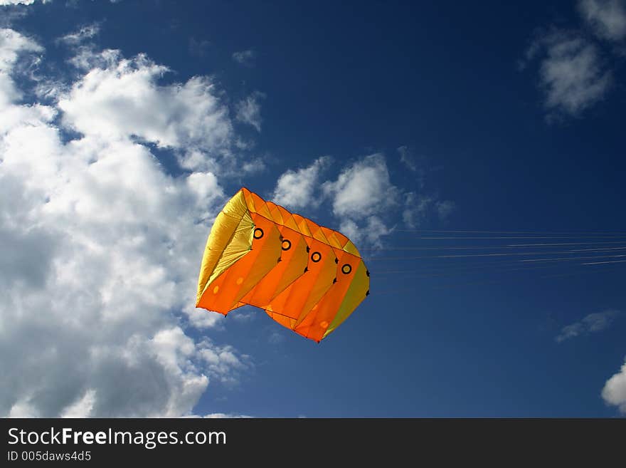 Orange kite next to the clouds