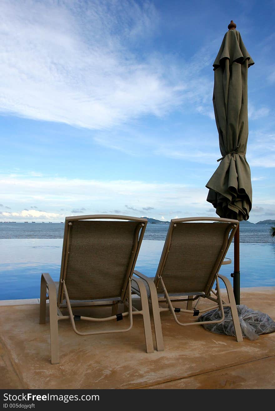 Some chairs on a beach front pool waiting for you to sit on them. Some chairs on a beach front pool waiting for you to sit on them