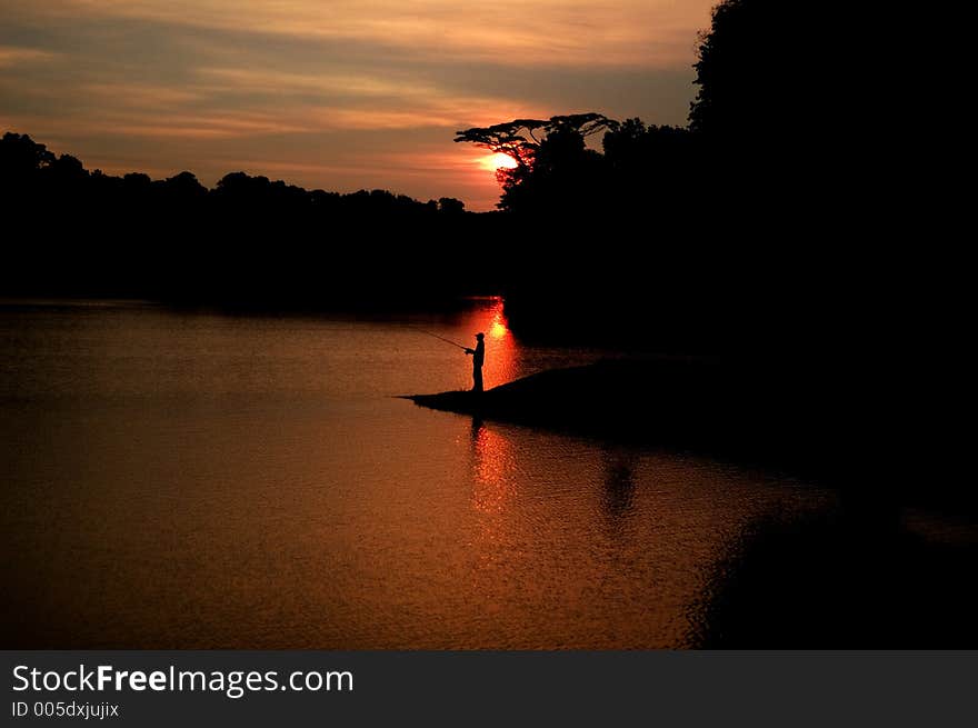 A Man Fishing During The Sunset. A Man Fishing During The Sunset