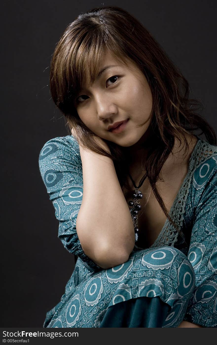 A beautiful young asian woman posing on a stool on black background. A beautiful young asian woman posing on a stool on black background