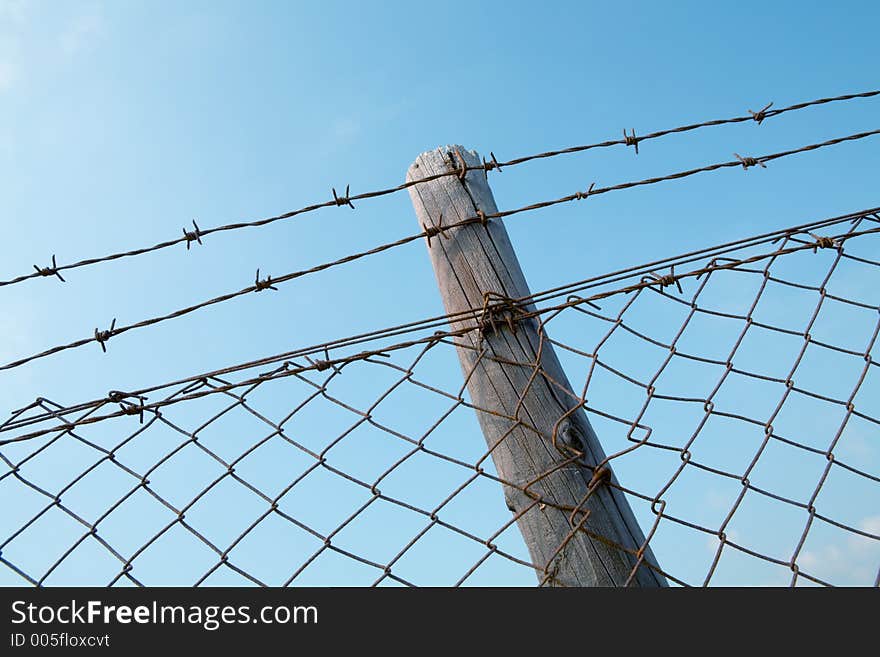 Barbed wire fence against blue sky