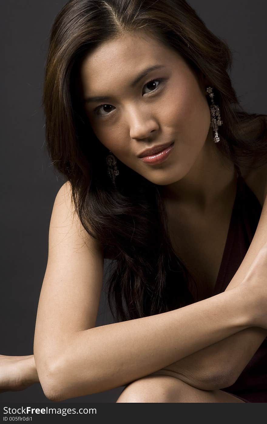 A pretty young asian model sitting with arms across her chest. A pretty young asian model sitting with arms across her chest