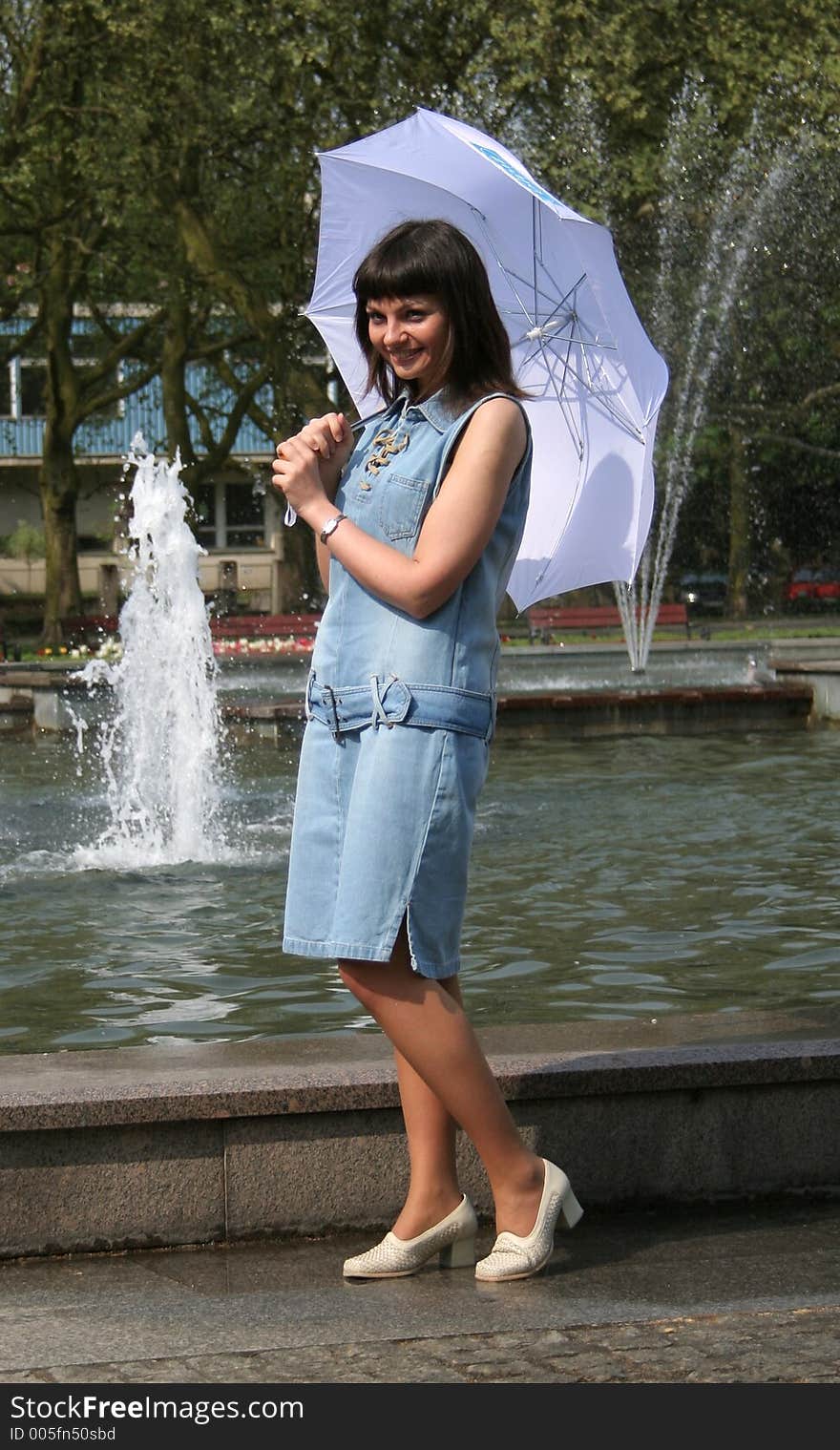 Pretty young woman with umbrella standing near fountain. Pretty young woman with umbrella standing near fountain