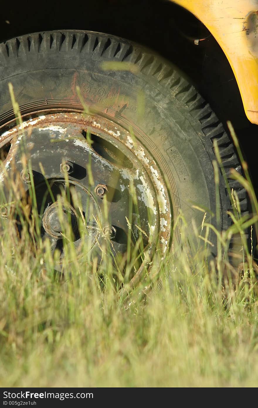 Abandoned truck image; telephoto shot of tyre (or tire) shot through grass. Abandoned truck image; telephoto shot of tyre (or tire) shot through grass.