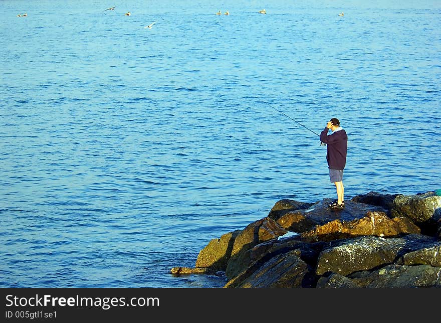 Man fishing on the rocks at beach