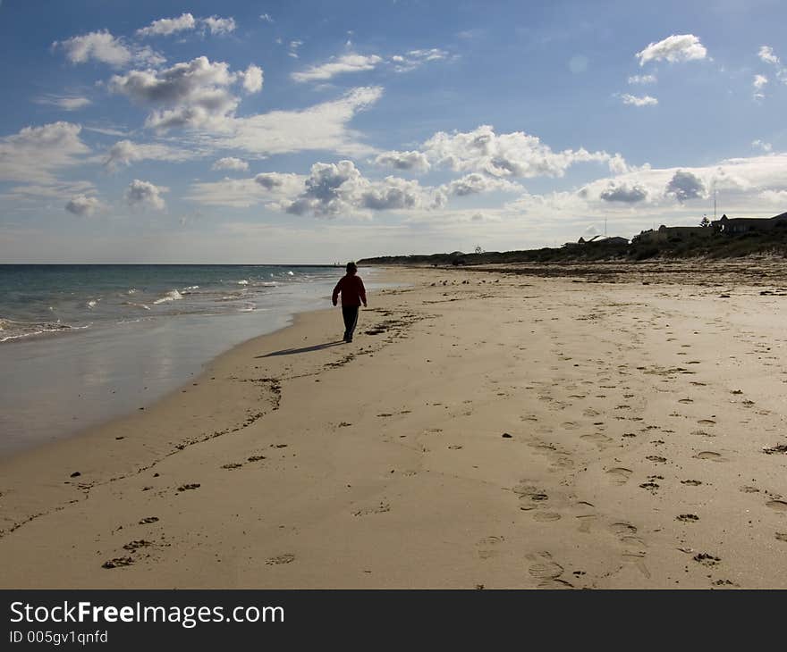 A boy walks along a secluded beach. A boy walks along a secluded beach