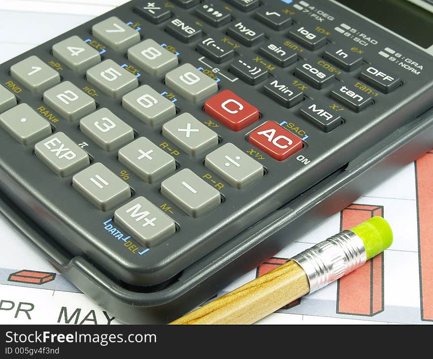 A composition of pencil and one calculator over a sales graph. A composition of pencil and one calculator over a sales graph