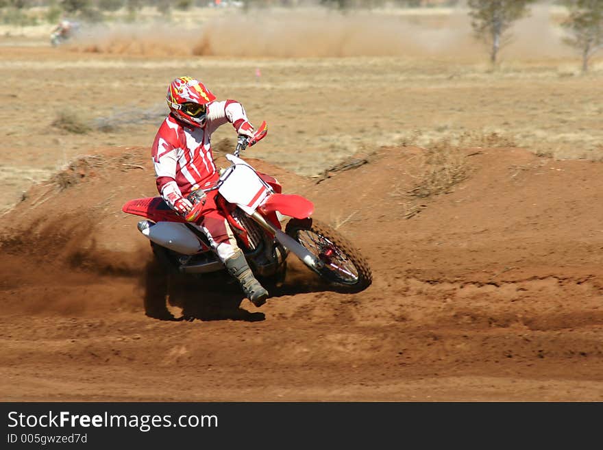 A motorbike races around the bend while a competitor races to catch up in the background, kicking up dirt along the way. Removed all logos and numbers for commercial use. A motorbike races around the bend while a competitor races to catch up in the background, kicking up dirt along the way. Removed all logos and numbers for commercial use.