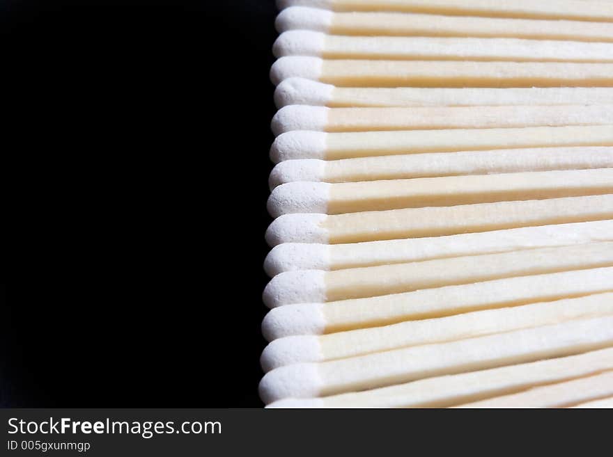 Closeup of wooden matches in a straight line isolated against a black background. Closeup of wooden matches in a straight line isolated against a black background.