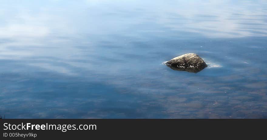 Lone rock in water.