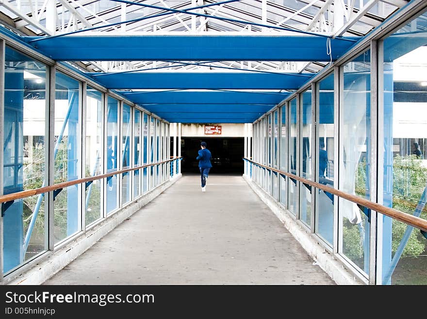 A teenager running through a glassed in overpass.