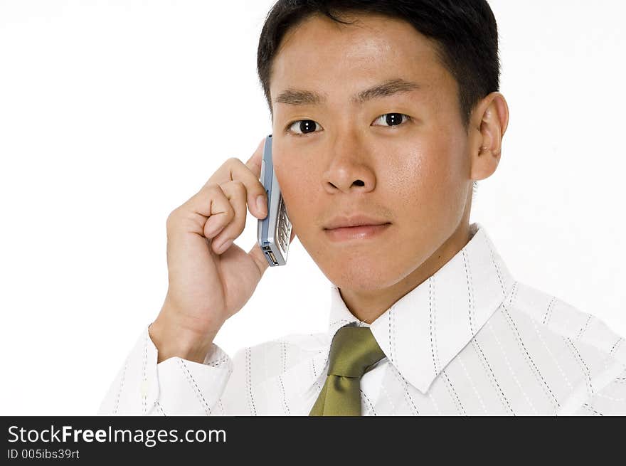 A serious young asian businessman on a cellphone. A serious young asian businessman on a cellphone