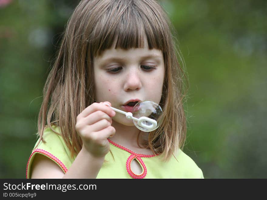 Girl blowing bubbles on bubble wand. Girl blowing bubbles on bubble wand