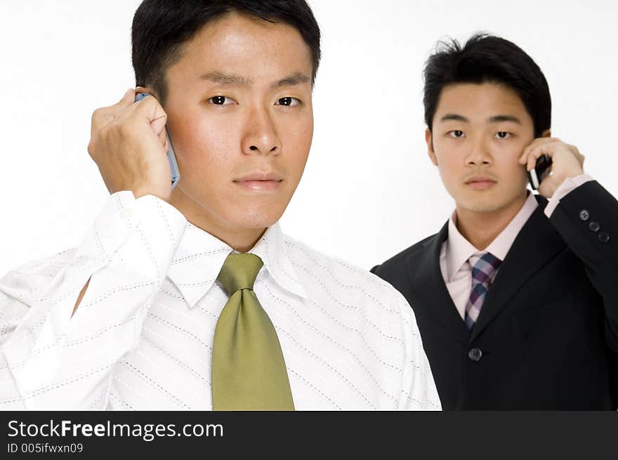 Two young asian businessmen using their phones. Two young asian businessmen using their phones