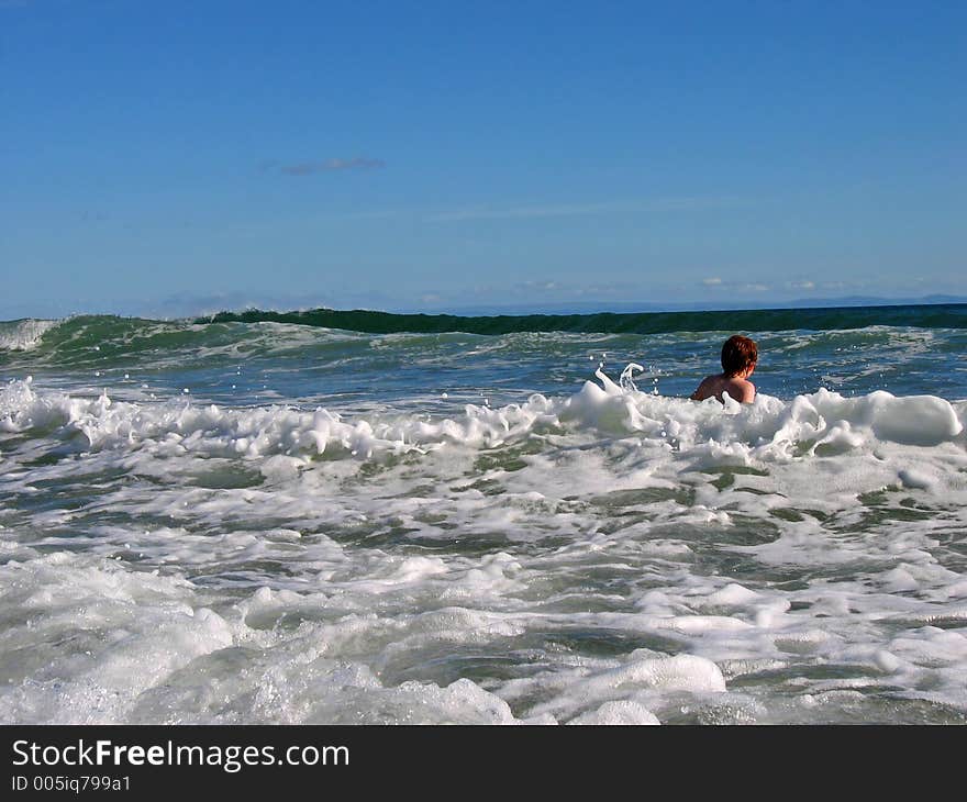 Little girl playing in the waves at the ocean in summer. Gower, south wales UK. Little girl playing in the waves at the ocean in summer. Gower, south wales UK