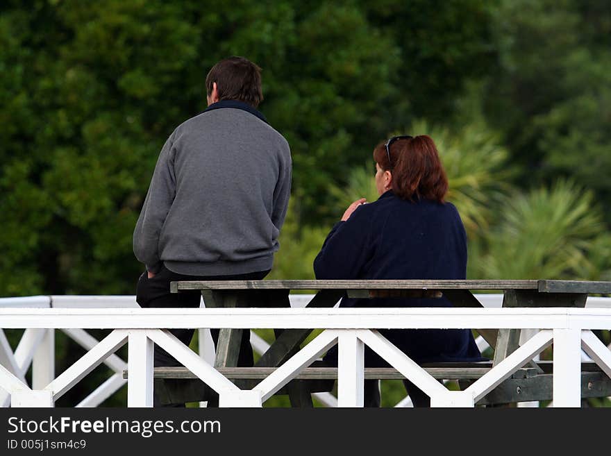 Man and woman talking on a bench, from behind. Man and woman talking on a bench, from behind