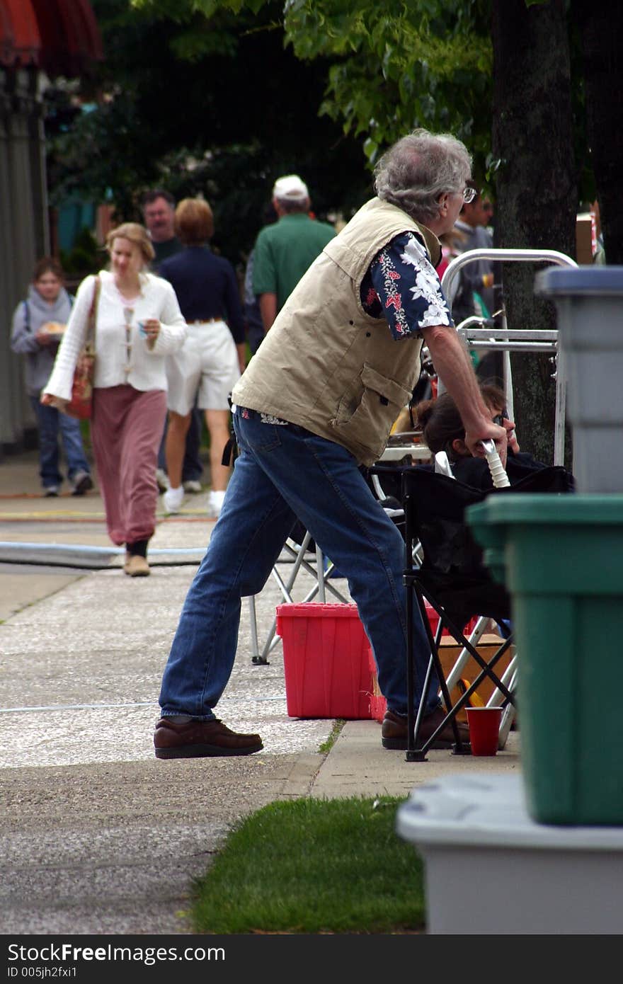 A man artist looks at the crowds that are passing by the front of his tent. A man artist looks at the crowds that are passing by the front of his tent