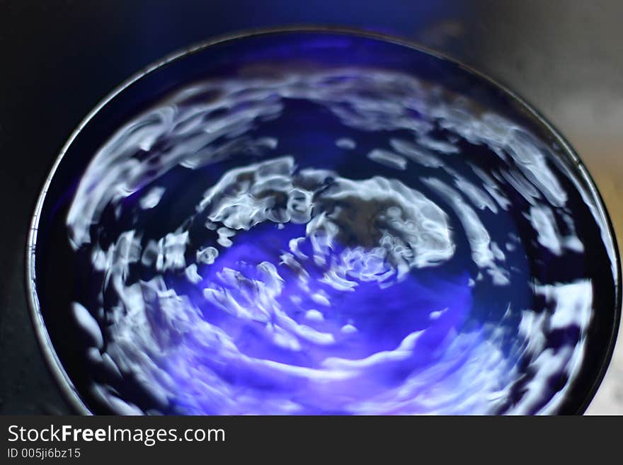 Close-up of water drop into blue bowl. Close-up of water drop into blue bowl.