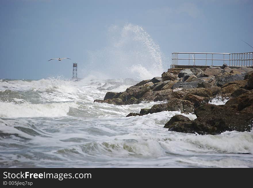 A pelican glides by as breakers crash against the jetty at Ponce Inlet Florida. A pelican glides by as breakers crash against the jetty at Ponce Inlet Florida