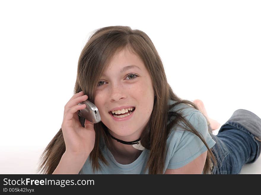 Cute tween or young teenage girl sitting on the floor and talking on a cellphone; shot on white. Cute tween or young teenage girl sitting on the floor and talking on a cellphone; shot on white