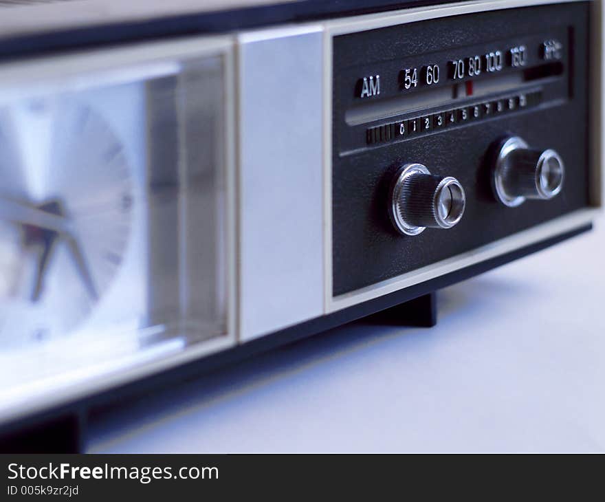 Vintage AM-band analog clock radio with radio dial in very shallow focus, in muted light. Vintage AM-band analog clock radio with radio dial in very shallow focus, in muted light.