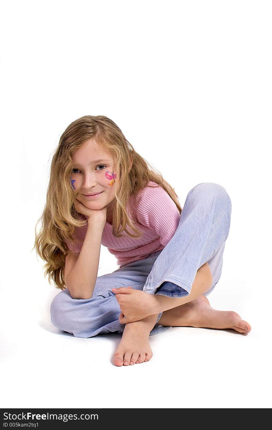 Beautiful young girl with a flower and butterfl drawing on her cheek sitting on the floor looking direct. Beautiful young girl with a flower and butterfl drawing on her cheek sitting on the floor looking direct