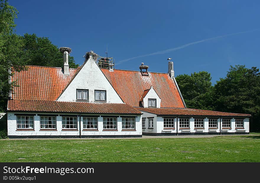 A white house. On the roof are some nest with storks.