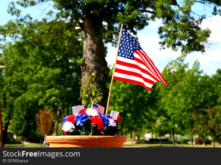 Red, white and blue carnation decoration with American flags in front of a large shade tree. Red, white and blue carnation decoration with American flags in front of a large shade tree