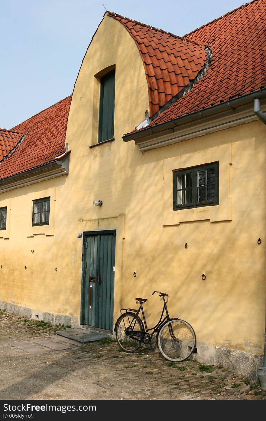 Large yellow l house a sunny summer day with a bike in a village in denmark. Large yellow l house a sunny summer day with a bike in a village in denmark