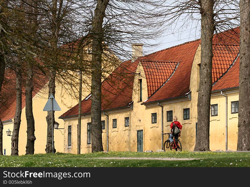 Large yellow l house   a sunny summer day with a boy on bike  in a village in denmark. Large yellow l house   a sunny summer day with a boy on bike  in a village in denmark