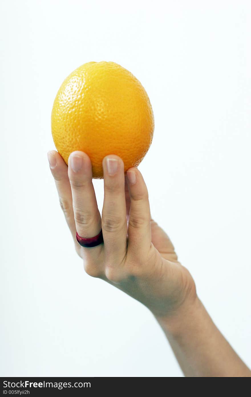 A woman's hand holding an orange. A woman's hand holding an orange.