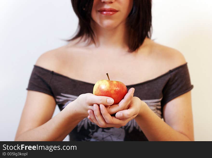 A beautiful young woman holding an apple in her hand. sharpness on the apple. A beautiful young woman holding an apple in her hand. sharpness on the apple.