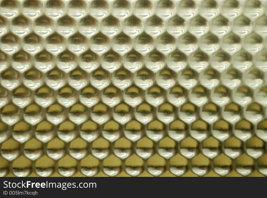 A reflective stamped metal texture with a honeycomb shape. A reflective stamped metal texture with a honeycomb shape